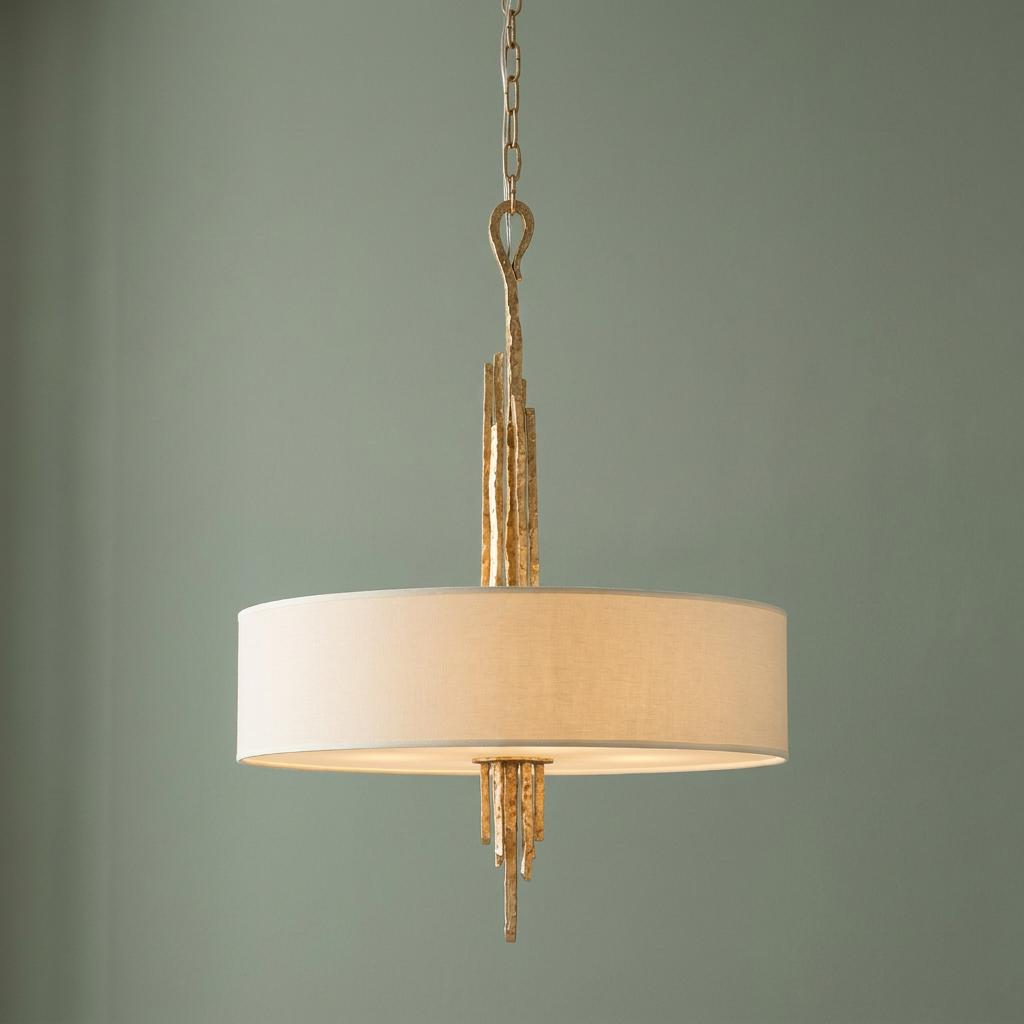 Champagne gold pendant light featuring a white drum shade and textured metalwork against a soft green background.