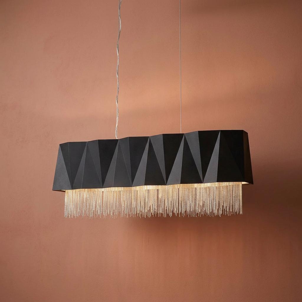 Faceted matte black geometric pendant light with hanging silver chain fringe against a terracotta wall.