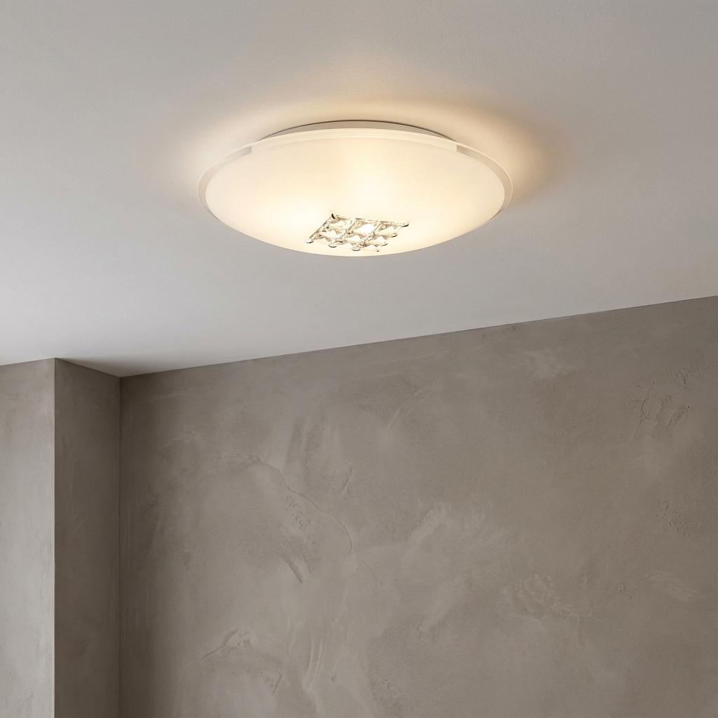 Horizon flush ceiling light featuring sanded glass and a crystal center, glowing against a grey wall.
