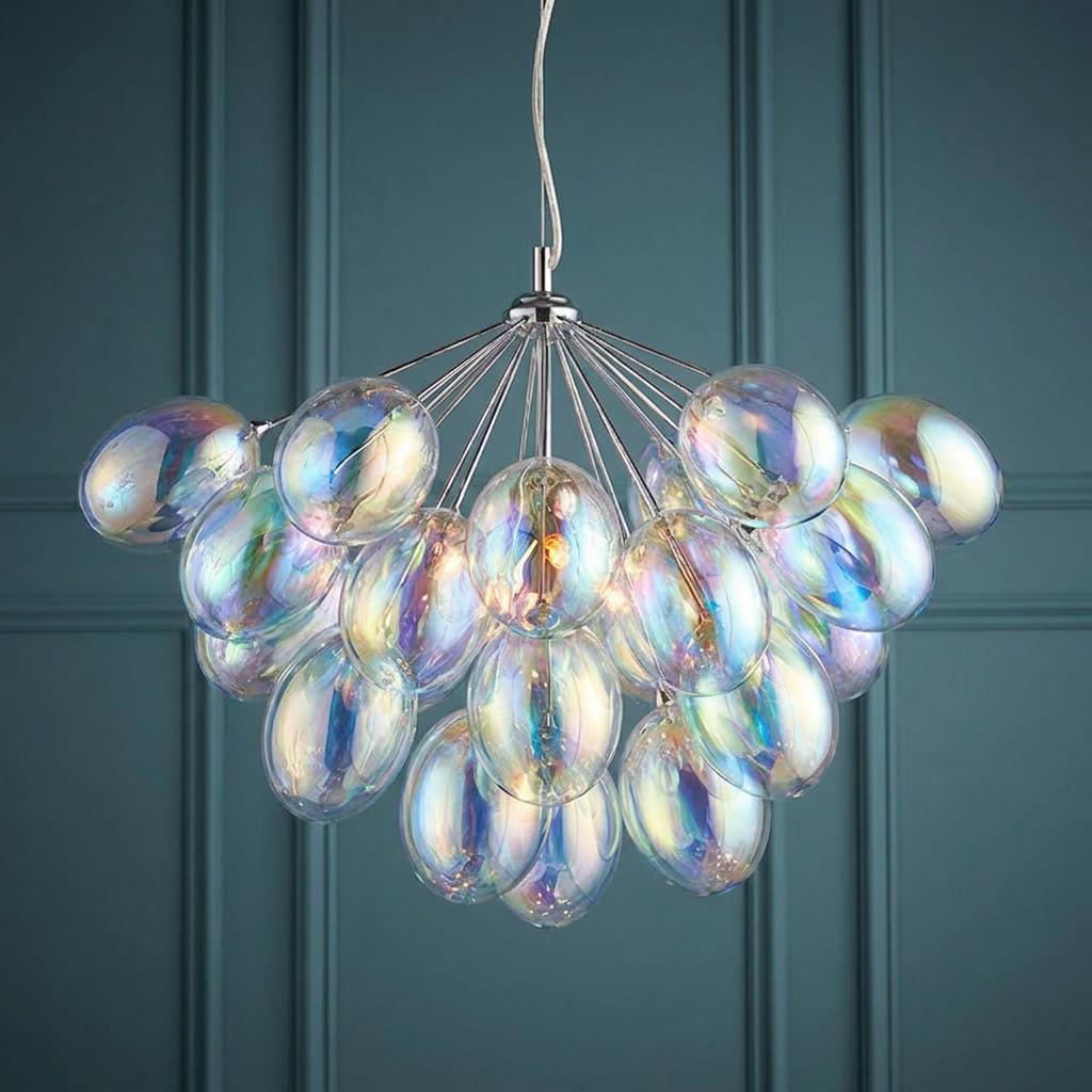 A chrome pendant light featuring a cluster of iridescent glass bubbles hanging against a dark teal paneled wall.