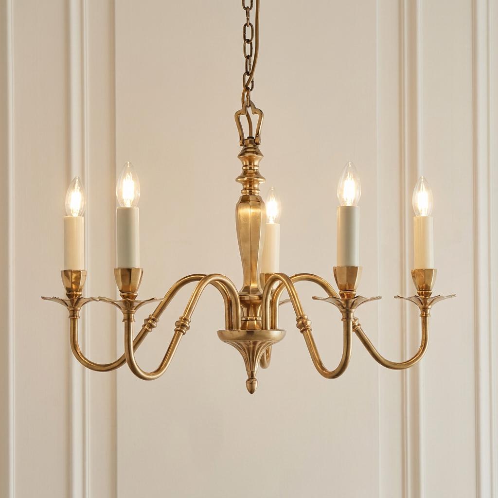 Interiors 1900 Asquith solid brass 5-light chandelier with candle-style bulbs against a white paneled wall.