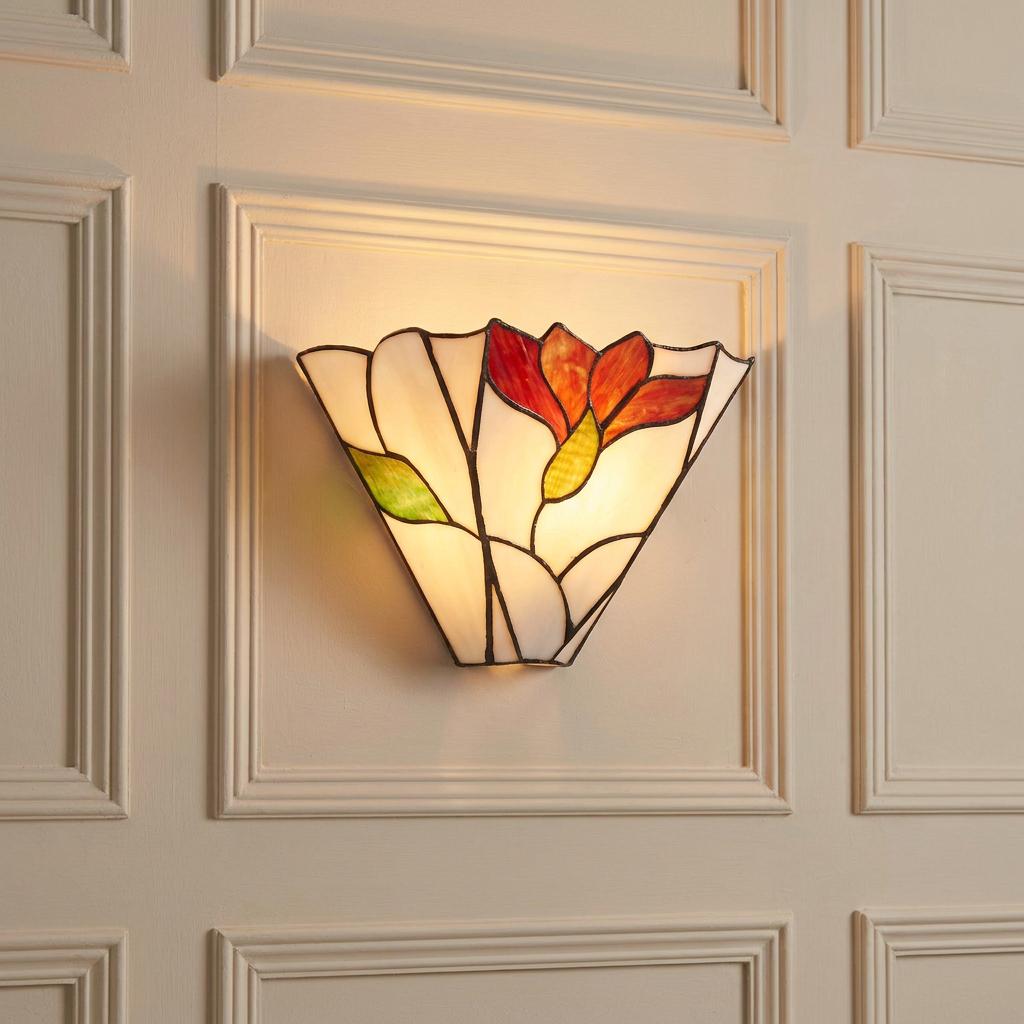 Botanica Tiffany wall light with a red floral design glowing on a cream paneled wall.