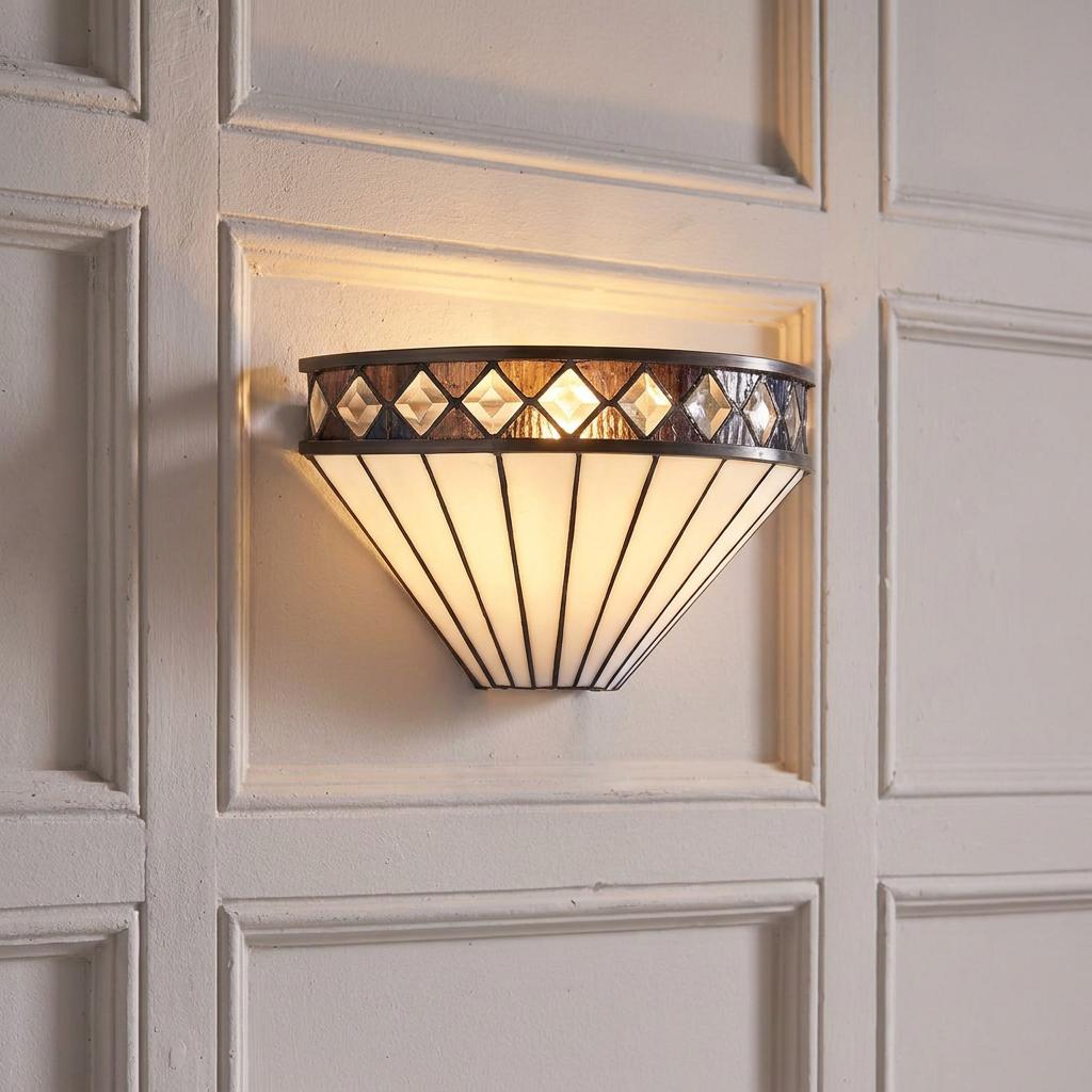 Art Deco fan-shaped Tiffany wall light with white glass panels and diamond trim lit on a white paneled wall.