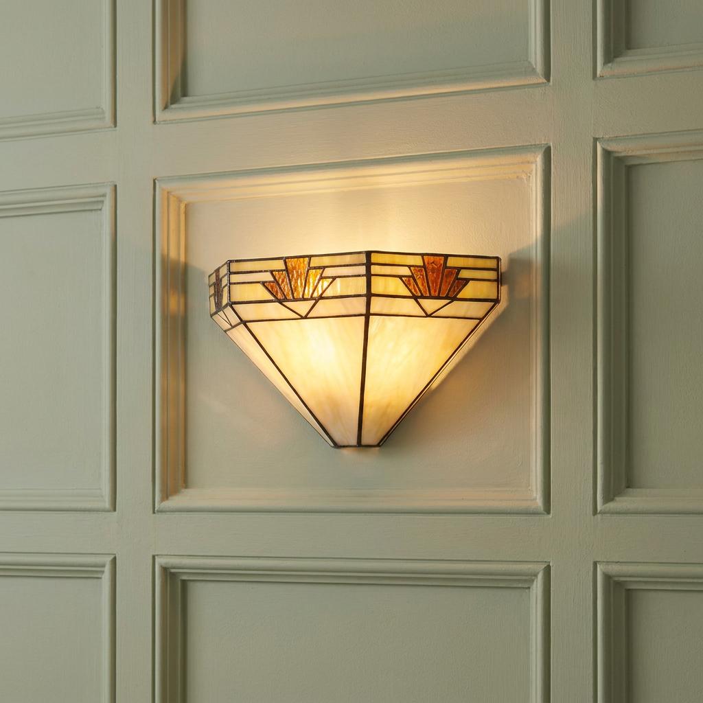 Art Deco Tiffany-style wall light with amber stained glass panels glowing on a light-colored paneled wall.