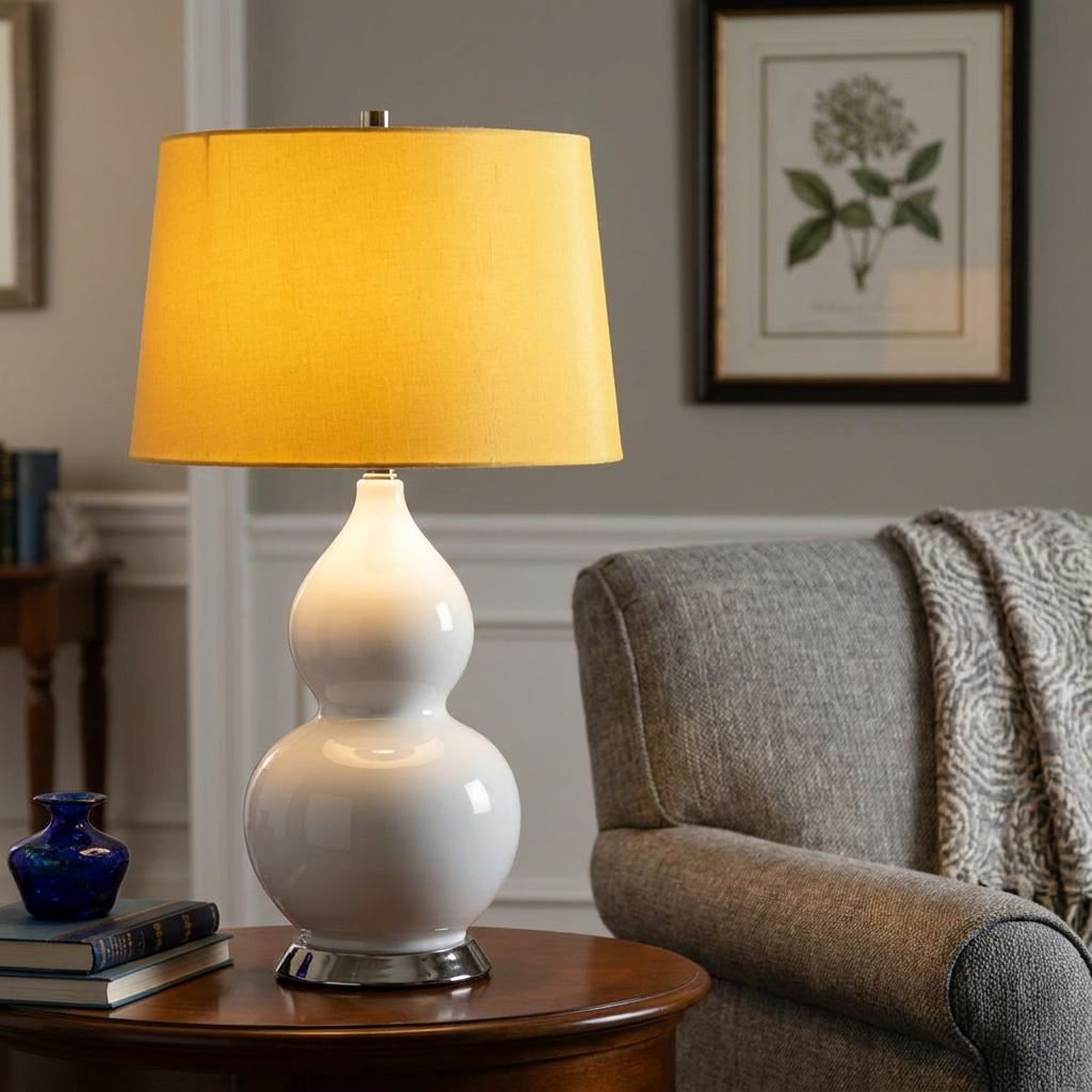 White gourd-shaped ceramic table lamp with a yellow shade on a wooden table in a living room.