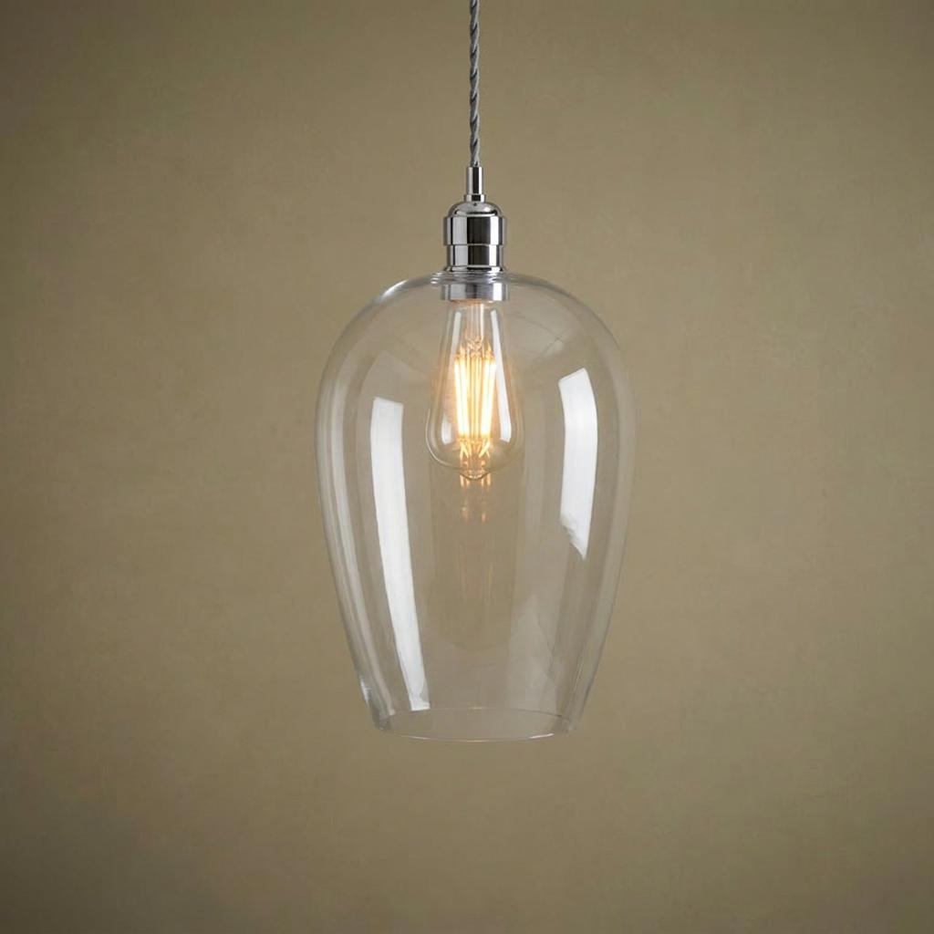 Clear glass teardrop pendant light with polished nickel hardware and a warm filament bulb.