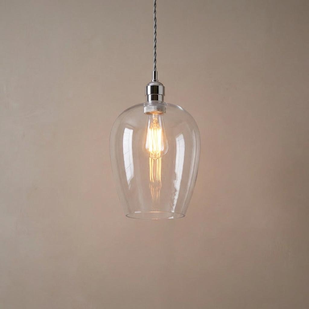 Art Deco ceiling pendant with an Island Nickel finish and a clear glass tapered shade housing a glowing filament bulb.