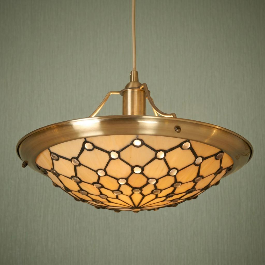 Jewel Easy Fit Tiffany ceiling lamp shade with glowing cream glass and brass frame against textured green wallpaper.