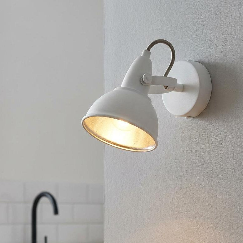 White wall-mounted spotlight with gold inner lining illuminating a modern kitchen countertop.