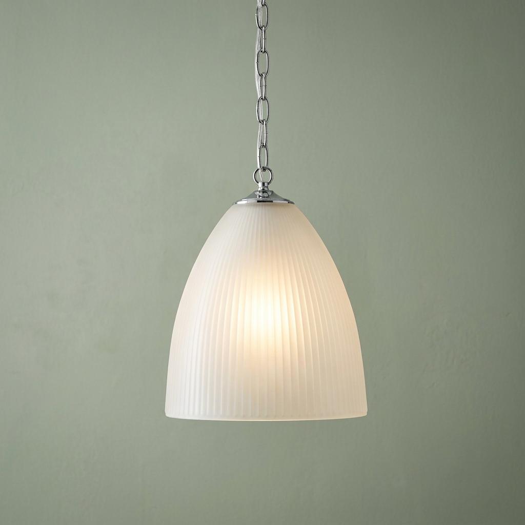 Elongated prismatic glass pendant light with a chrome chain hanging against a pale green wall.