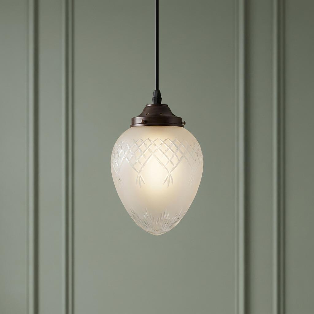 Kansa Pinestar medium acorn pendant light with etched frosted glass against a sage green paneled wall.