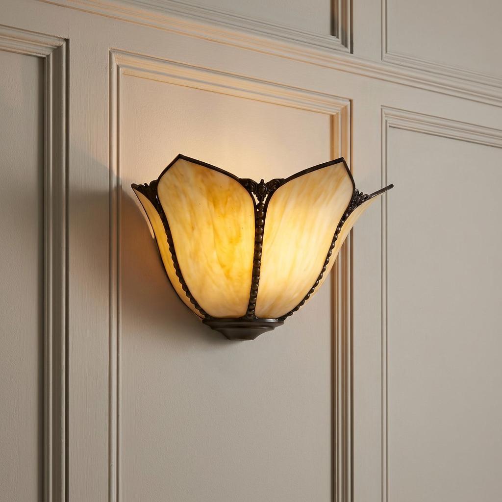 Amber Tiffany wall light with tulip-shaped glass panels illuminated on a cream paneled wall.