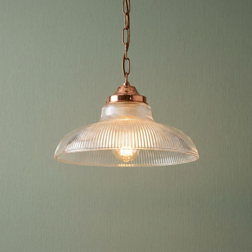 Prismatic glass pendant light with a copper chain and gallery hanging against a textured sage green wall.