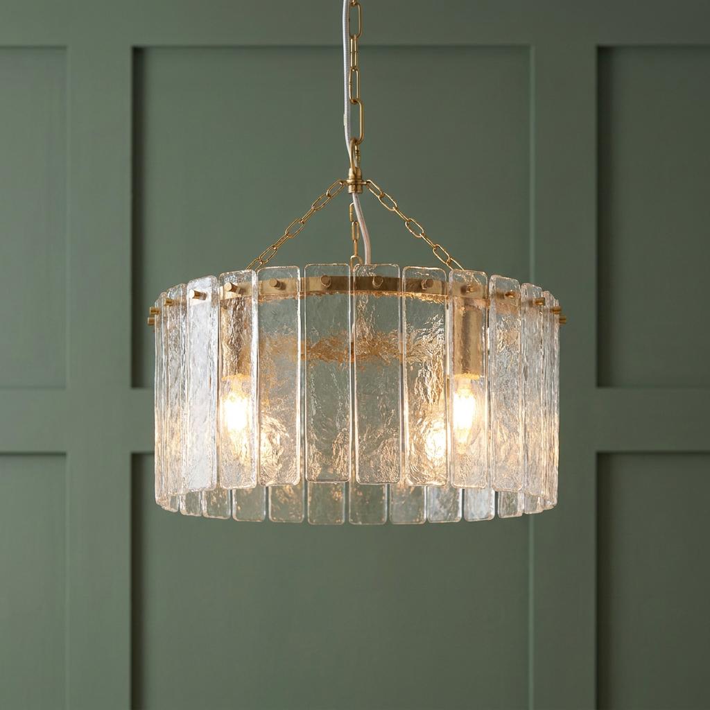 Karine 3 light brass pendant with handmade glass panels hanging against a dark green paneled wall.