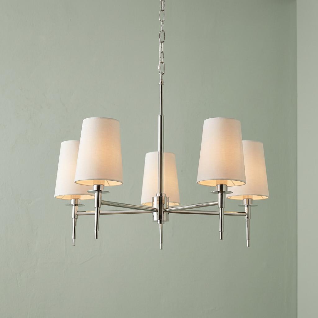 Kensington five-light nickel pendant with white tapered shades illuminated against a pale green wall.
