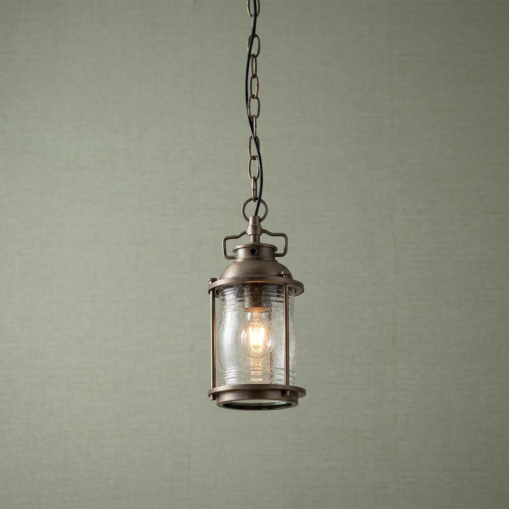 Kichler Ashland Bay small bronze outdoor chain lantern with seeded glass shade and warm glowing bulb.