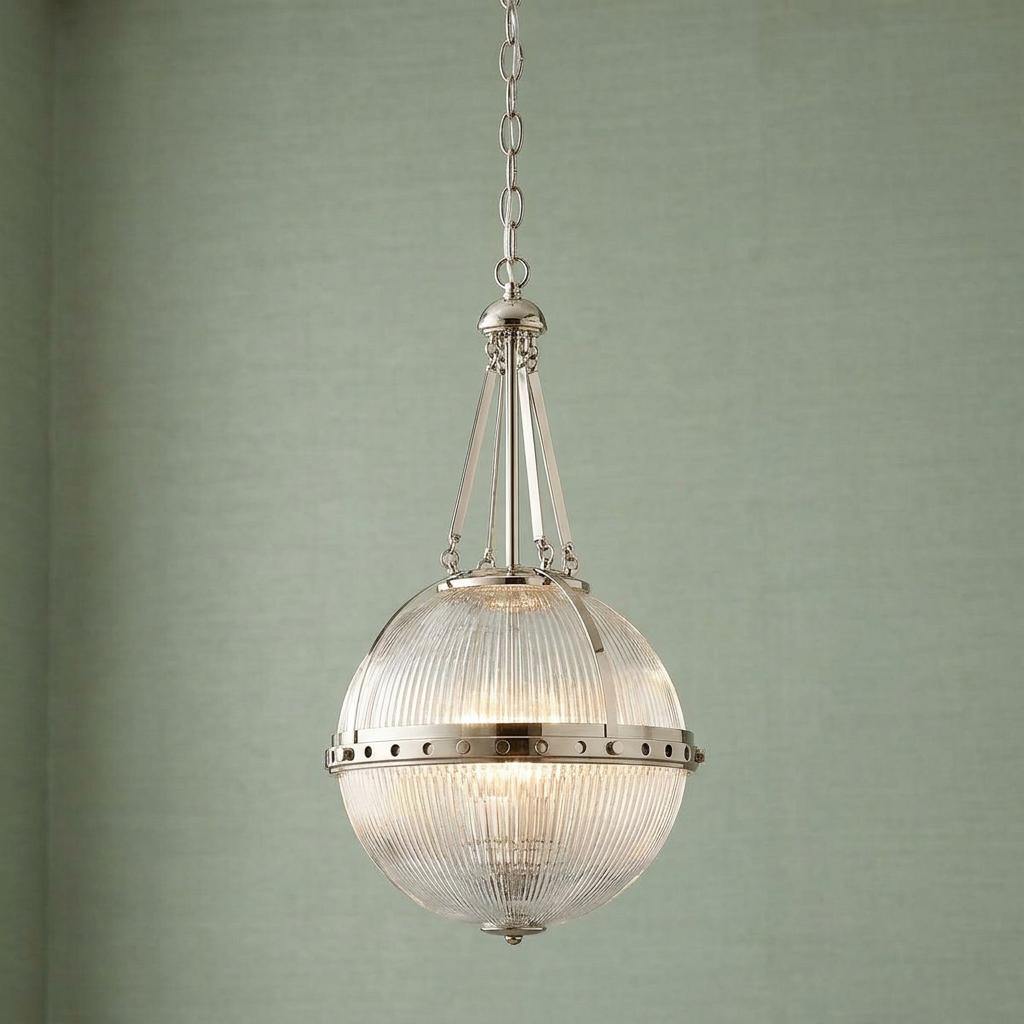 Three-light polished nickel pendant with a ribbed glass globe shade against a pale green wall.