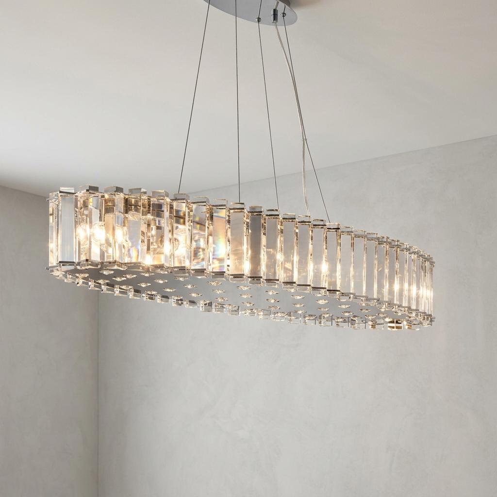 Oval chrome island pendant light with vertical crystal prisms hanging from a ceiling in a modern room.