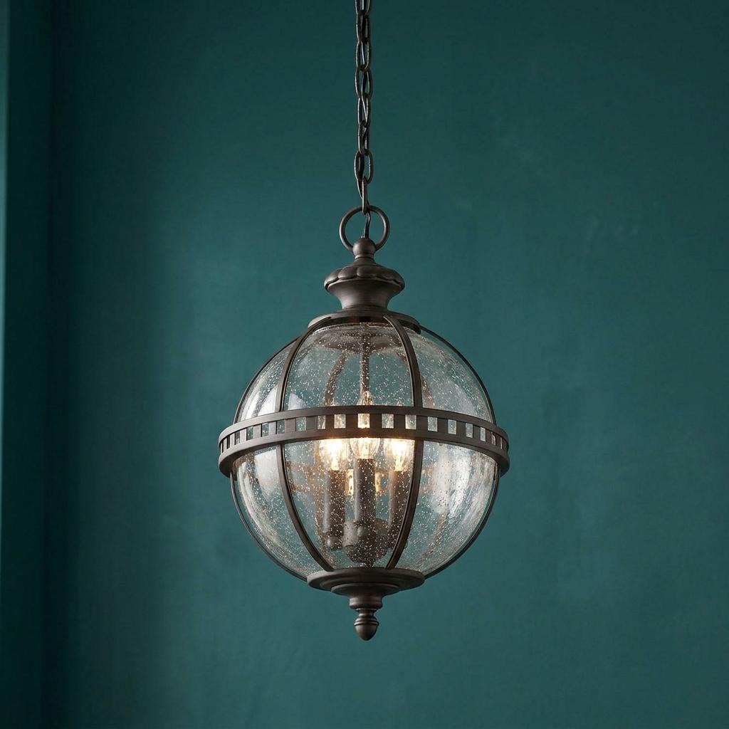 Spherical grey outdoor pendant light with seeded glass and three bulbs, hanging against a dark teal textured wall.