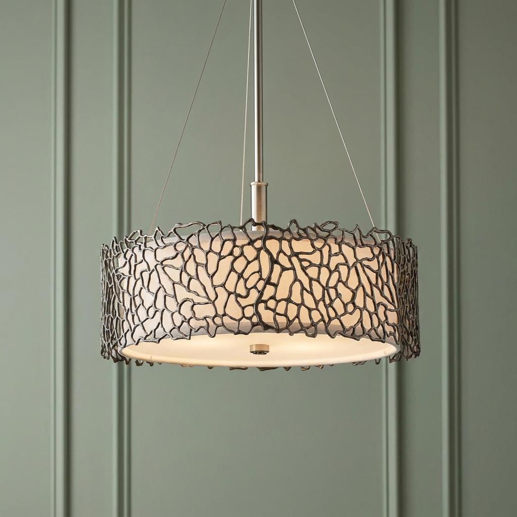Pewter coral-patterned pendant light with a white drum shade hanging against a green paneled wall.
