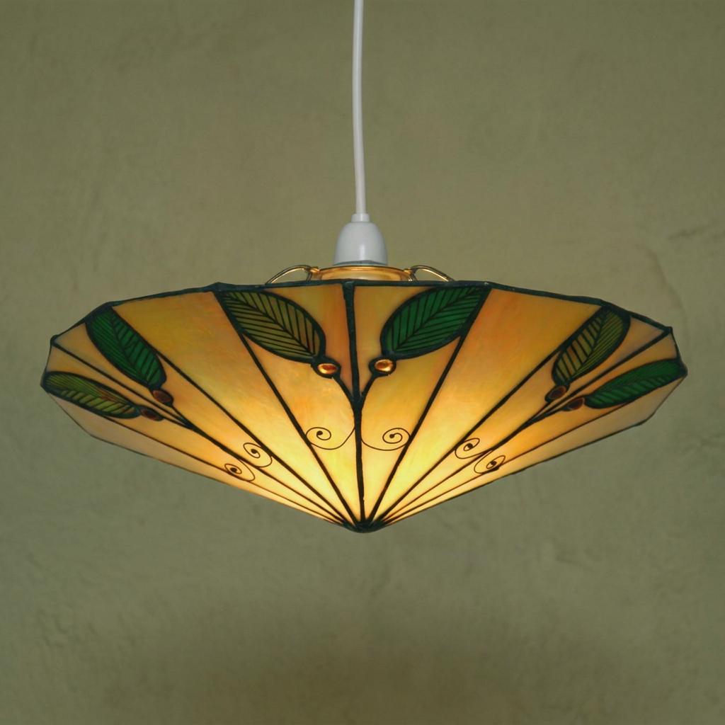 Illuminated Tiffany ceiling lamp shade featuring green leaf patterns on amber glass.