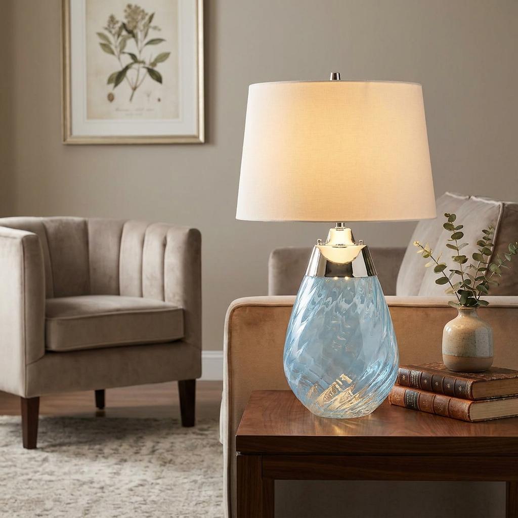 Lena 2 light small blue glass table lamp with an off-white drum shade on a wooden side table in a living room.