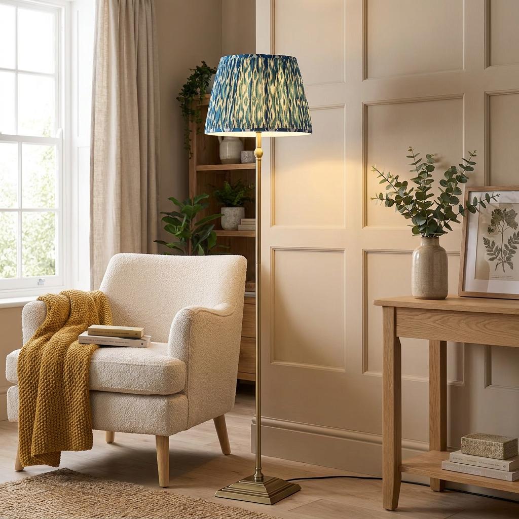 Lille brass floor lamp with a blue ikat shade in a cozy living room next to a white boucle armchair.