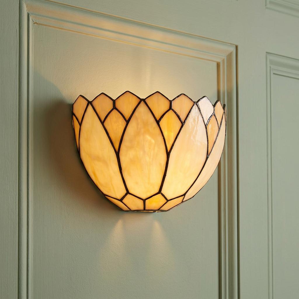 Lily-shaped Tiffany wall light with cream glass panels glowing on a pale green paneled wall.
