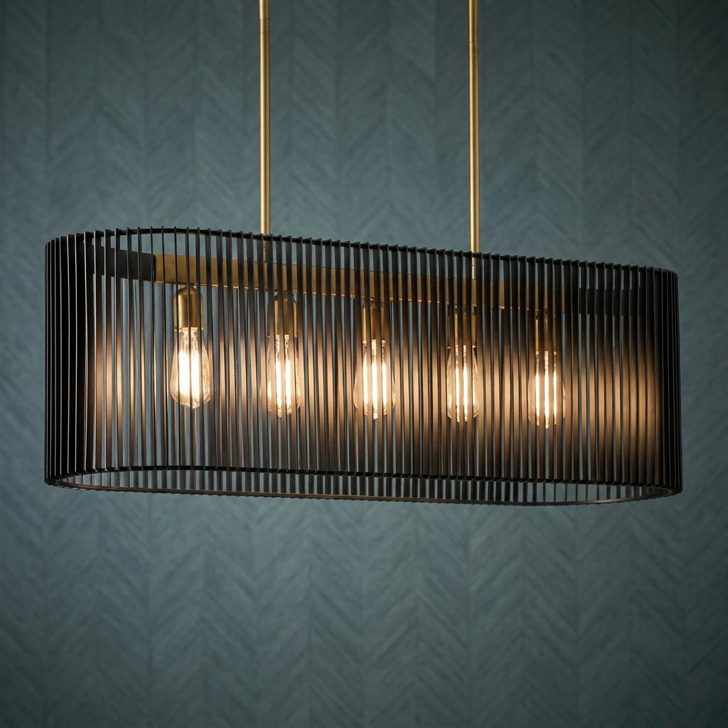 Modern linear chandelier with five glowing bulbs in a black slatted metal shade against a blue textured wall.