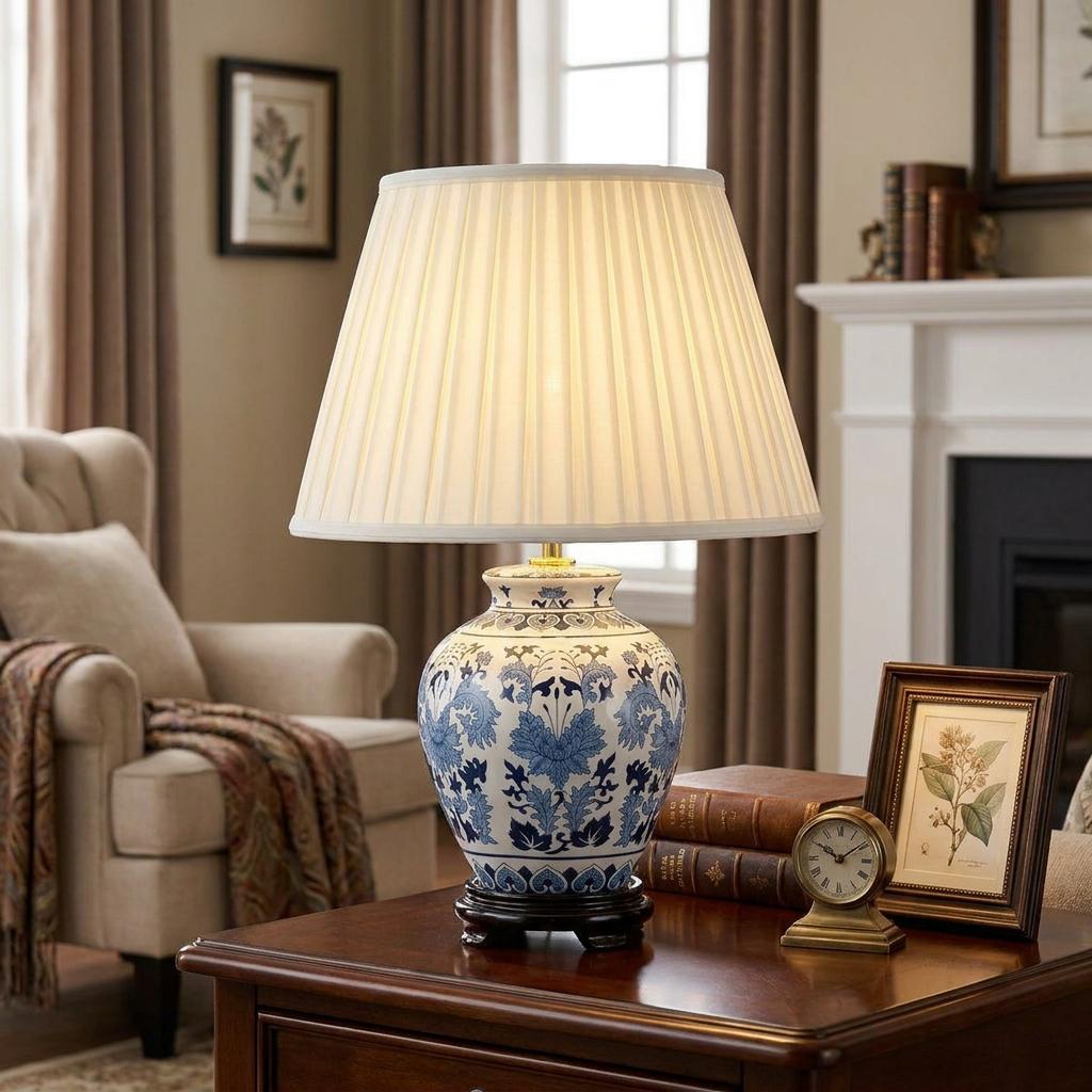 Blue and white floral ceramic table lamp with a pleated ivory shade on a wooden side table in a cozy living room.