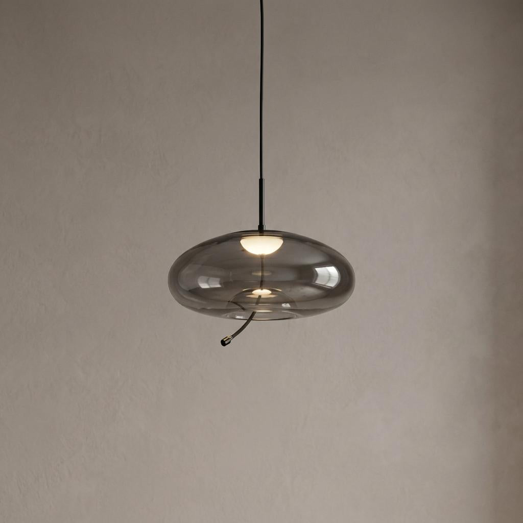 Lisbon black and smoked glass LED ceiling pendant light with a flat oval shade against a neutral wall.