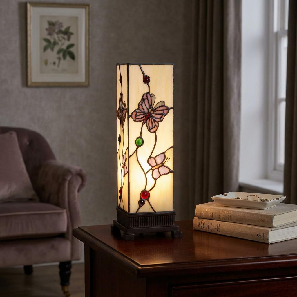 A lit square Tiffany table lamp with pink butterfly stained glass details sitting on a dark wood table.