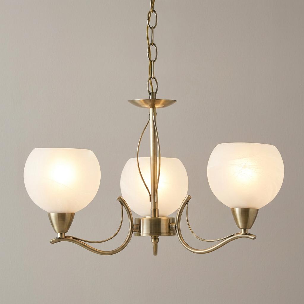 Antique brass pendant chandelier with three opal glass globe shades and curved metal arms hanging from a chain.