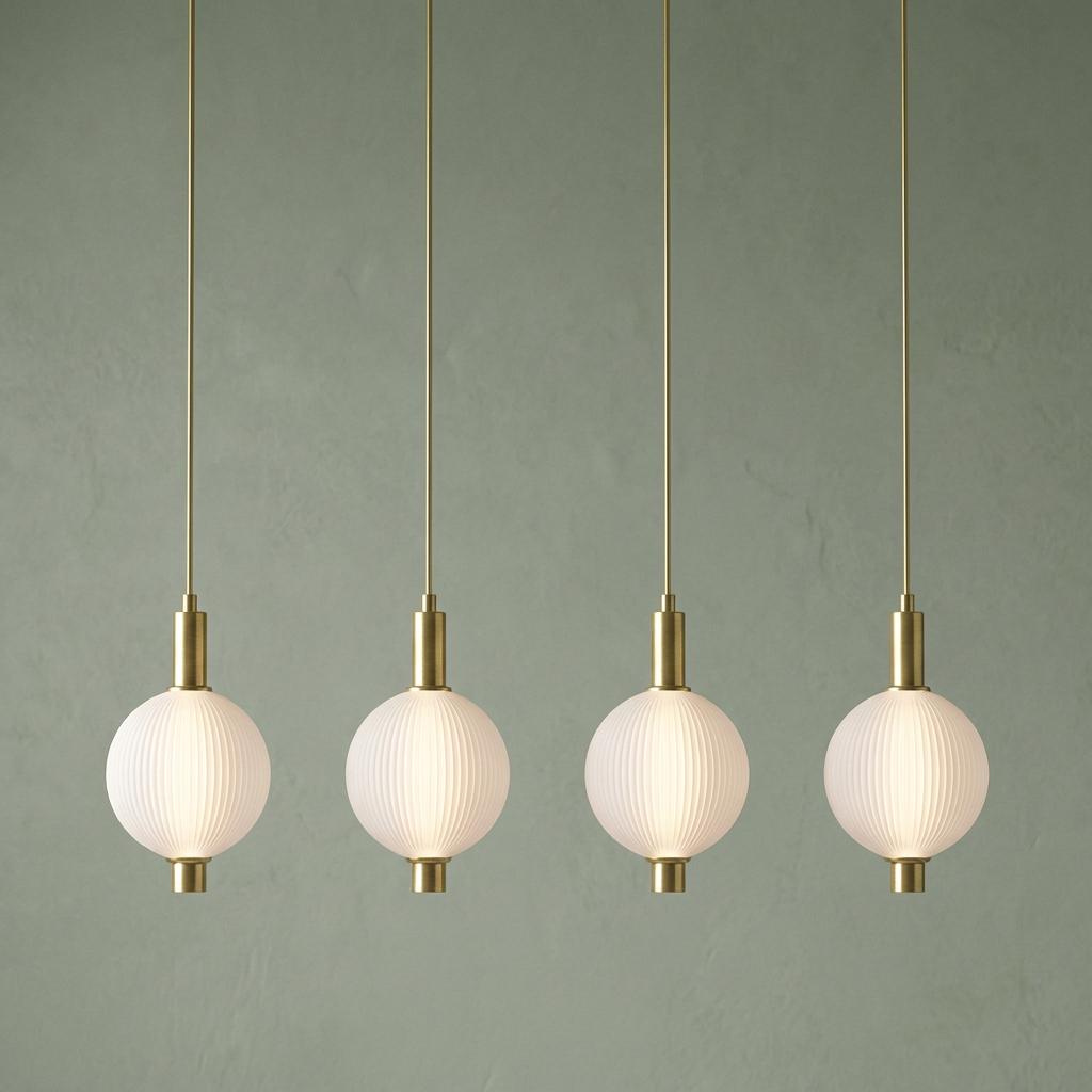 Four satin brass ceiling pendants with glowing ribbed glass globes hang against a sage green textured wall.