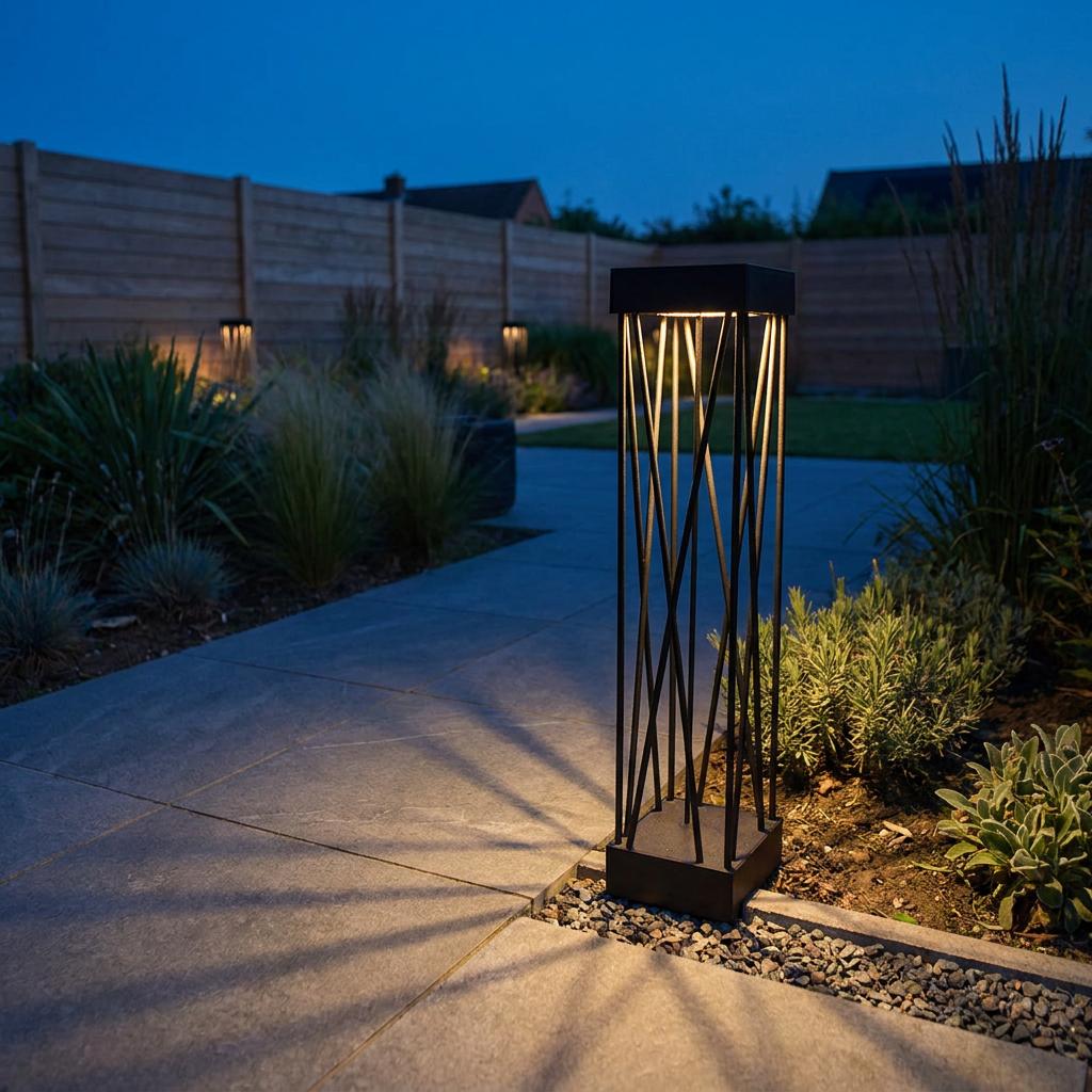 Modern black solar bollard light with a crisscross pattern glowing on a slate garden path at dusk.