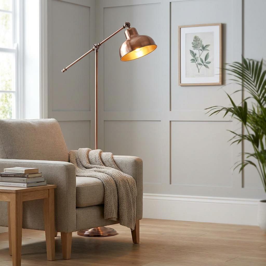 Macbeth copper industrial floor lamp positioned over a beige armchair in a panelled living room.