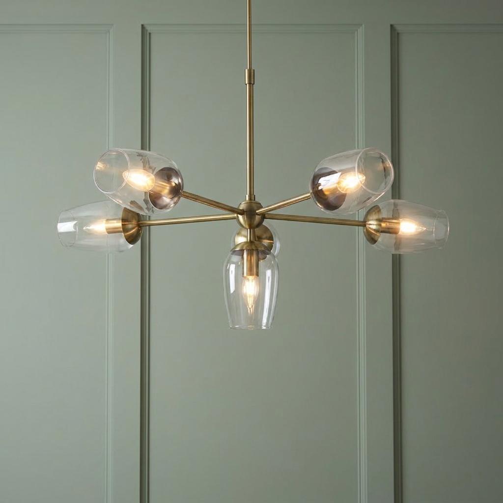 Maeve 6 light brass pendant with glass shades hanging against a green paneled wall.