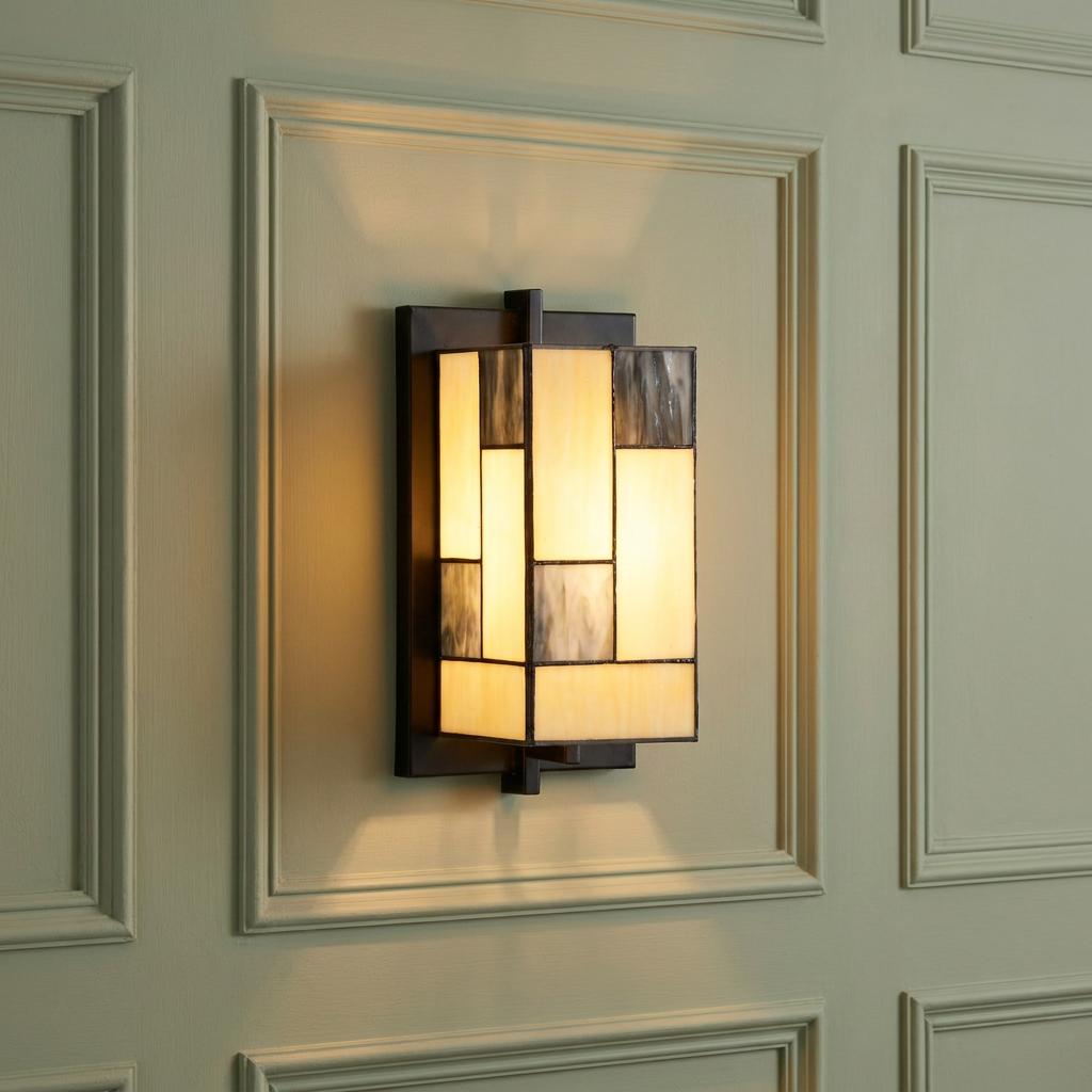Rectangular Tiffany wall light with geometric cream and grey glass panels mounted on a green paneled wall.