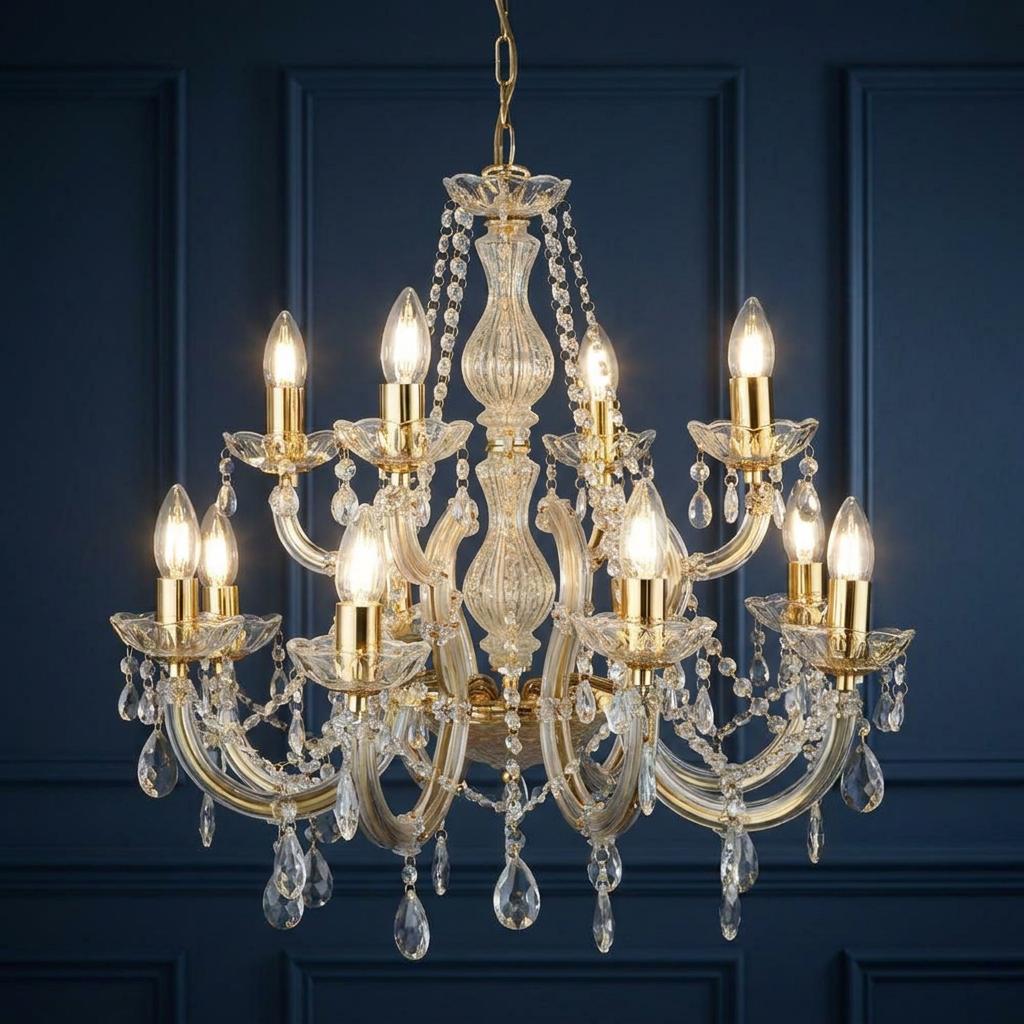 12-light brass and crystal glass chandelier with glowing bulbs against a dark blue paneled wall.