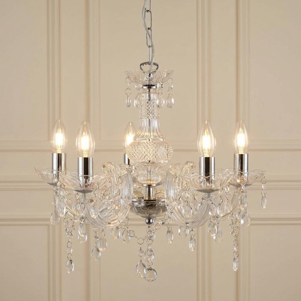 Marie Therese five-light chandelier with clear glass, acrylic accents, and hanging crystals on a cream paneled wall.