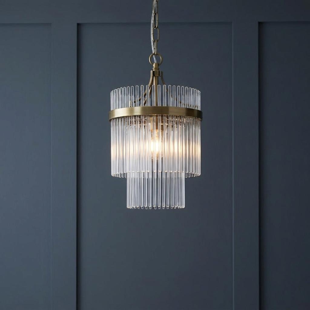Marietta brass small ceiling pendant with vertical glass rods illuminated against a dark blue paneled wall.