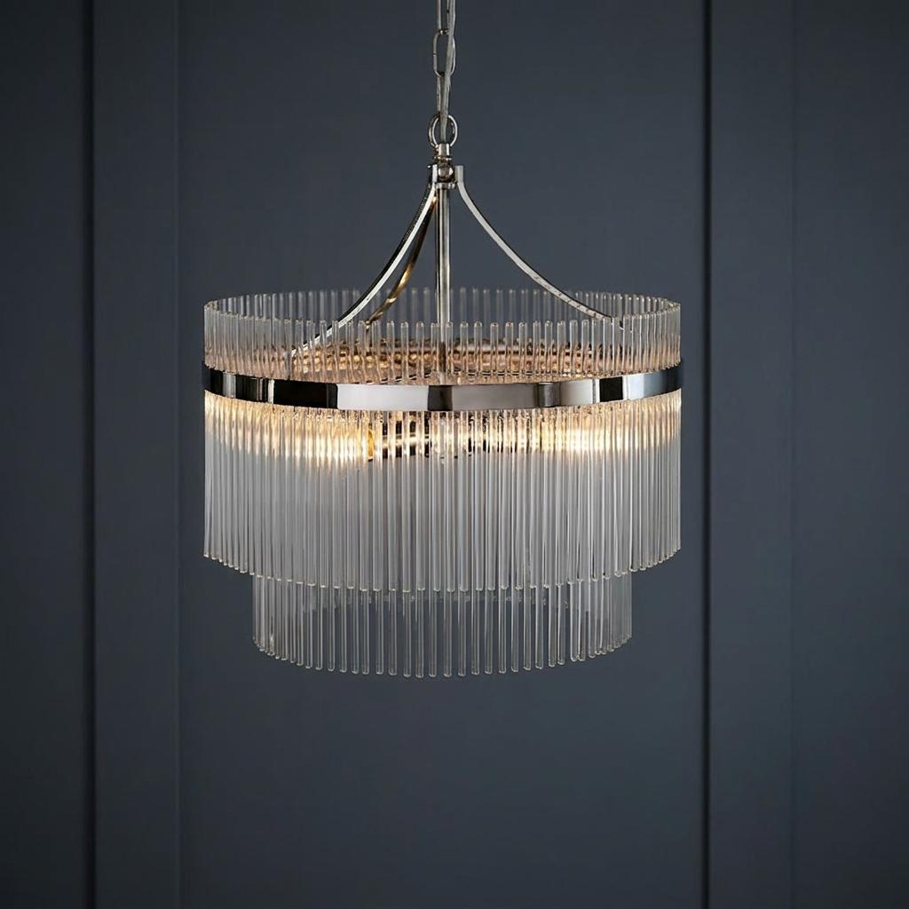 Two-tiered nickel chandelier with vertical glass rods illuminated against a dark paneled background.