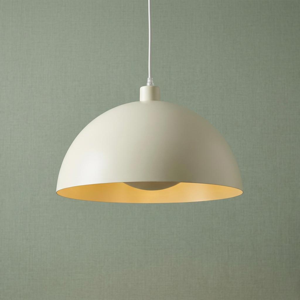 Matt cream dome pendant light with a warm interior glow, hanging against a textured green wall.