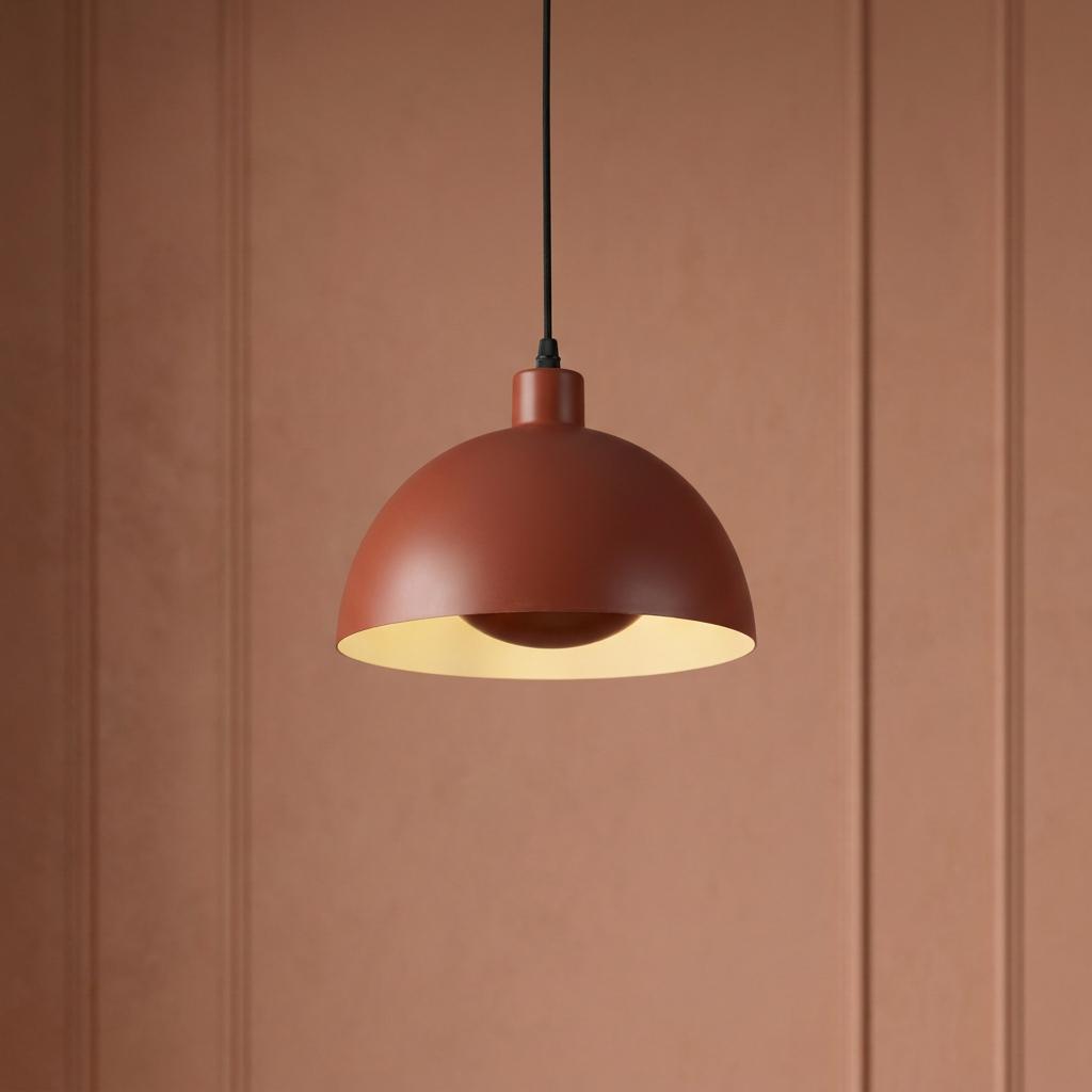 Mars burnt orange dome pendant light with cream inner surface against a terracotta paneled wall.
