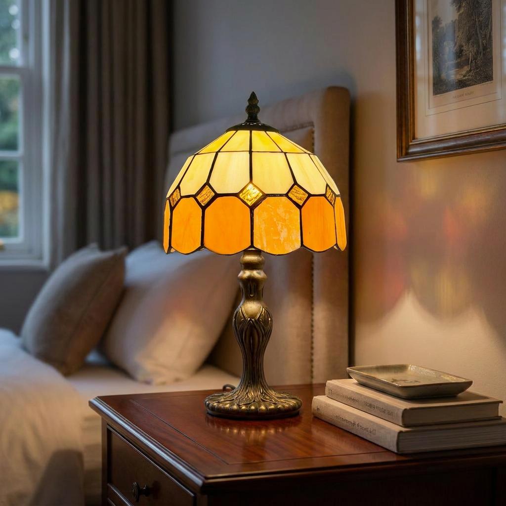 Martinsthorpe Tiffany lamp with an amber geometric glass shade on a wooden bedside table in a cozy bedroom.
