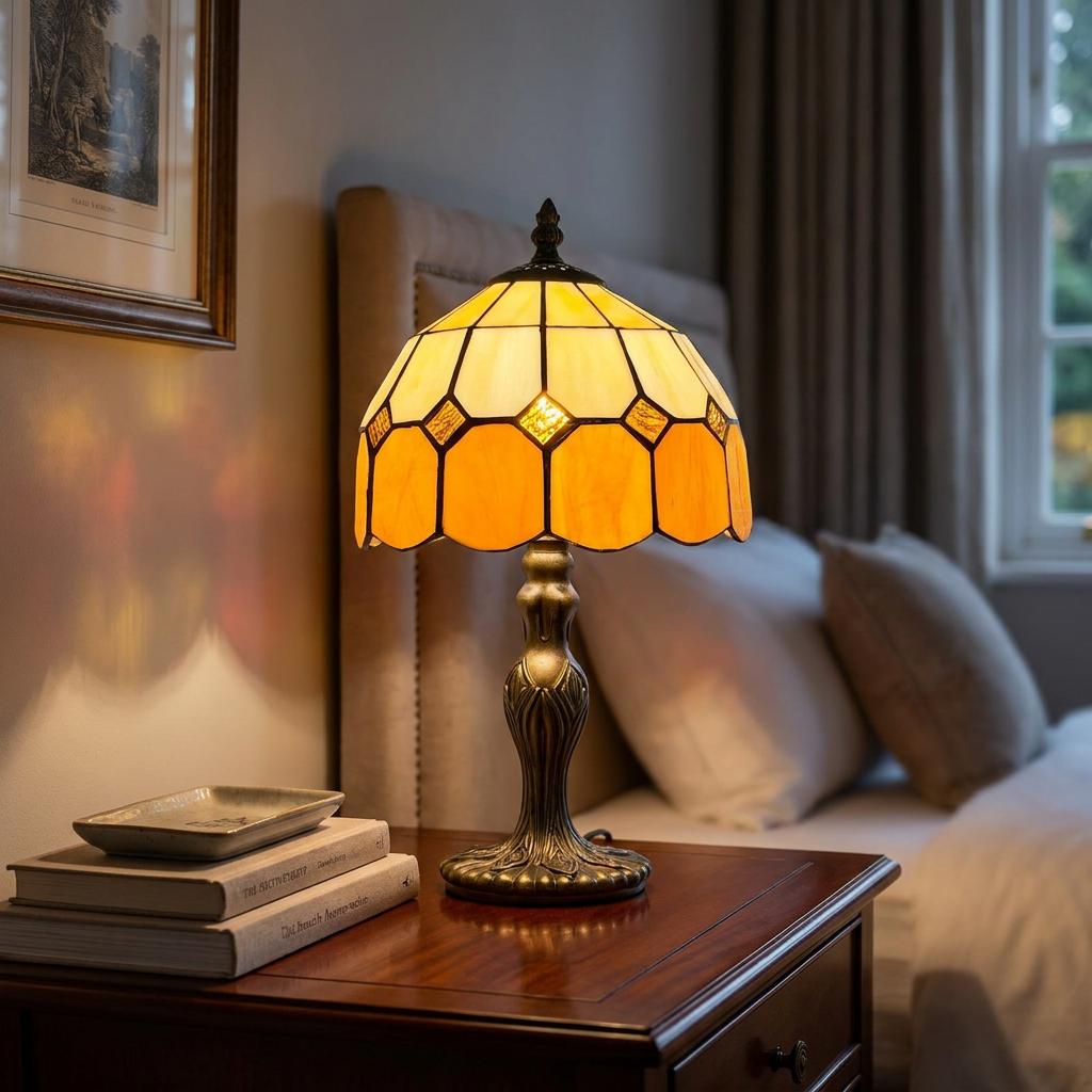 Martinsthorpe Tiffany bedside lamp with a glowing amber stained glass shade and ornate base on a wooden nightstand.