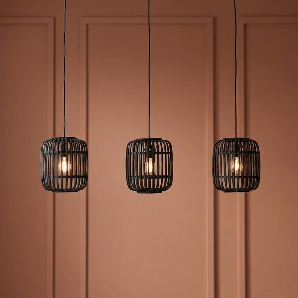 Three black bamboo cage pendant lights hanging against a terracotta paneled wall with warm glowing bulbs.