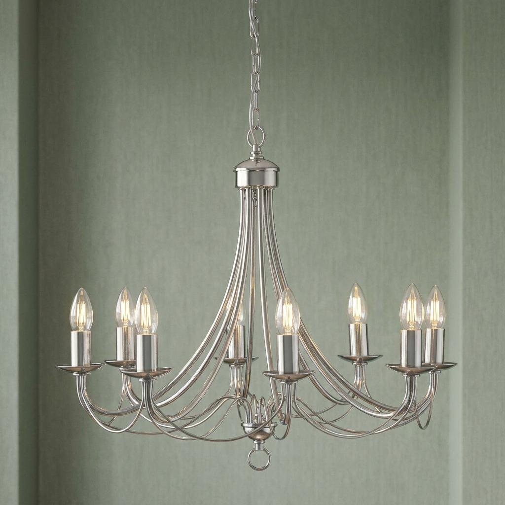 Eight-light satin silver chandelier with elegant curved arms and candle bulbs against a soft green textured wall.