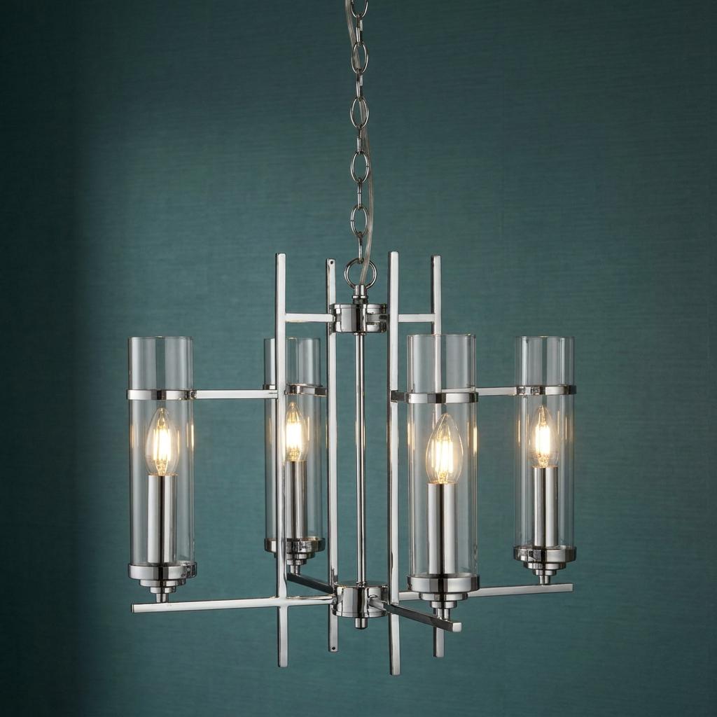 Milo four-light chrome ceiling pendant with glass cylinder shades lit against a dark teal wall.