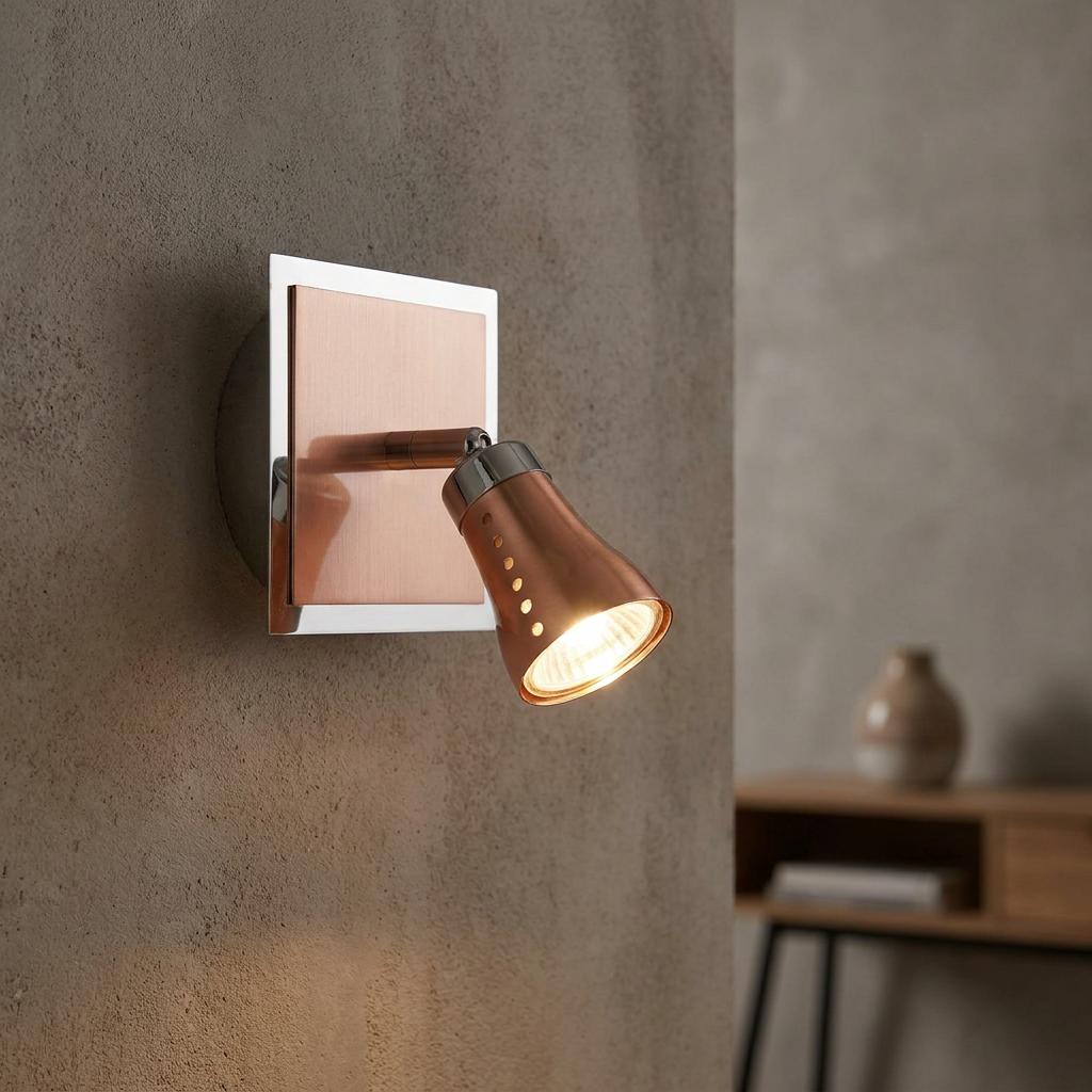 Milo Copper and Chrome adjustable wall-mounted spotlight illuminated against a textured grey wall.